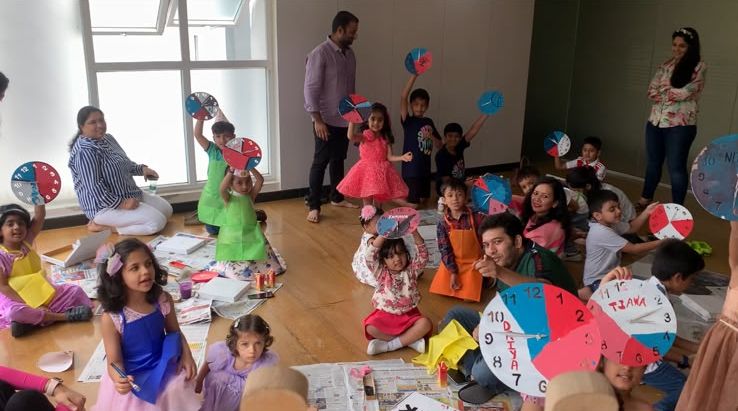 Kids holding up the paper clocks they made